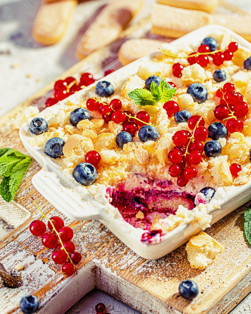 Beeren-Protein-Tiramisu in einer Glasschale mit frischen Beeren und zerbröseltem Löffelbiskuit