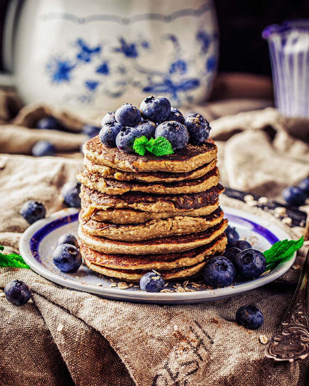 Gestapelte Blaubeer-Pancakes mit frischen Blaubeeren, Minze und Honig